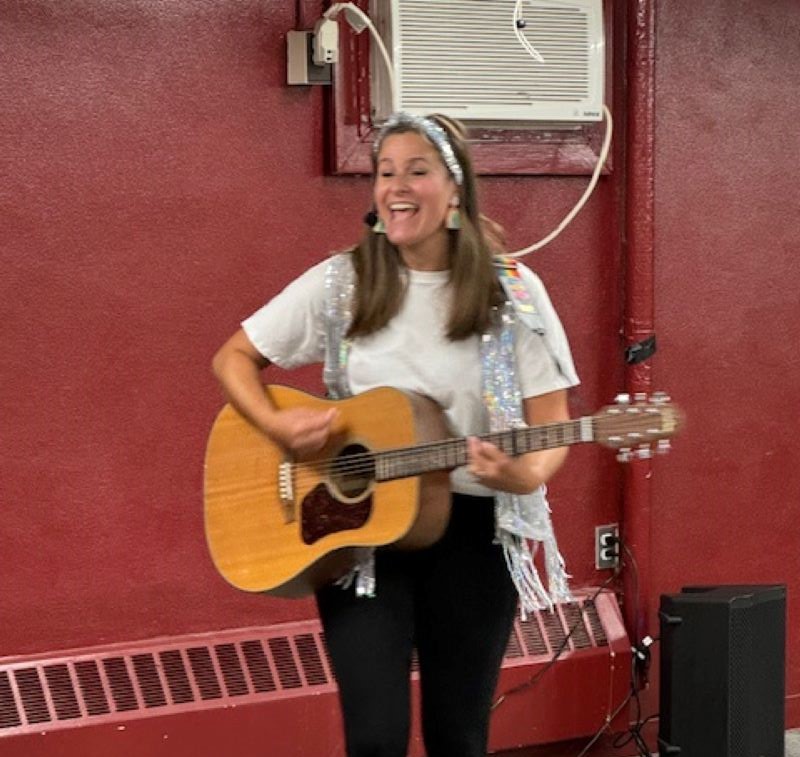 Miss Ari with a guitar singing a song.