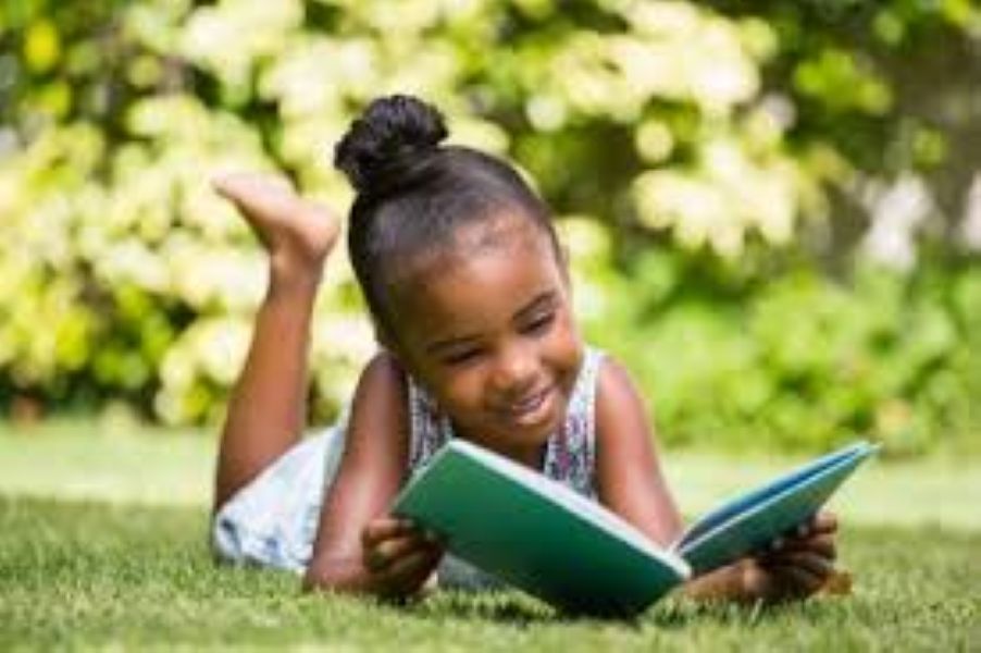 Little girl reading outside.