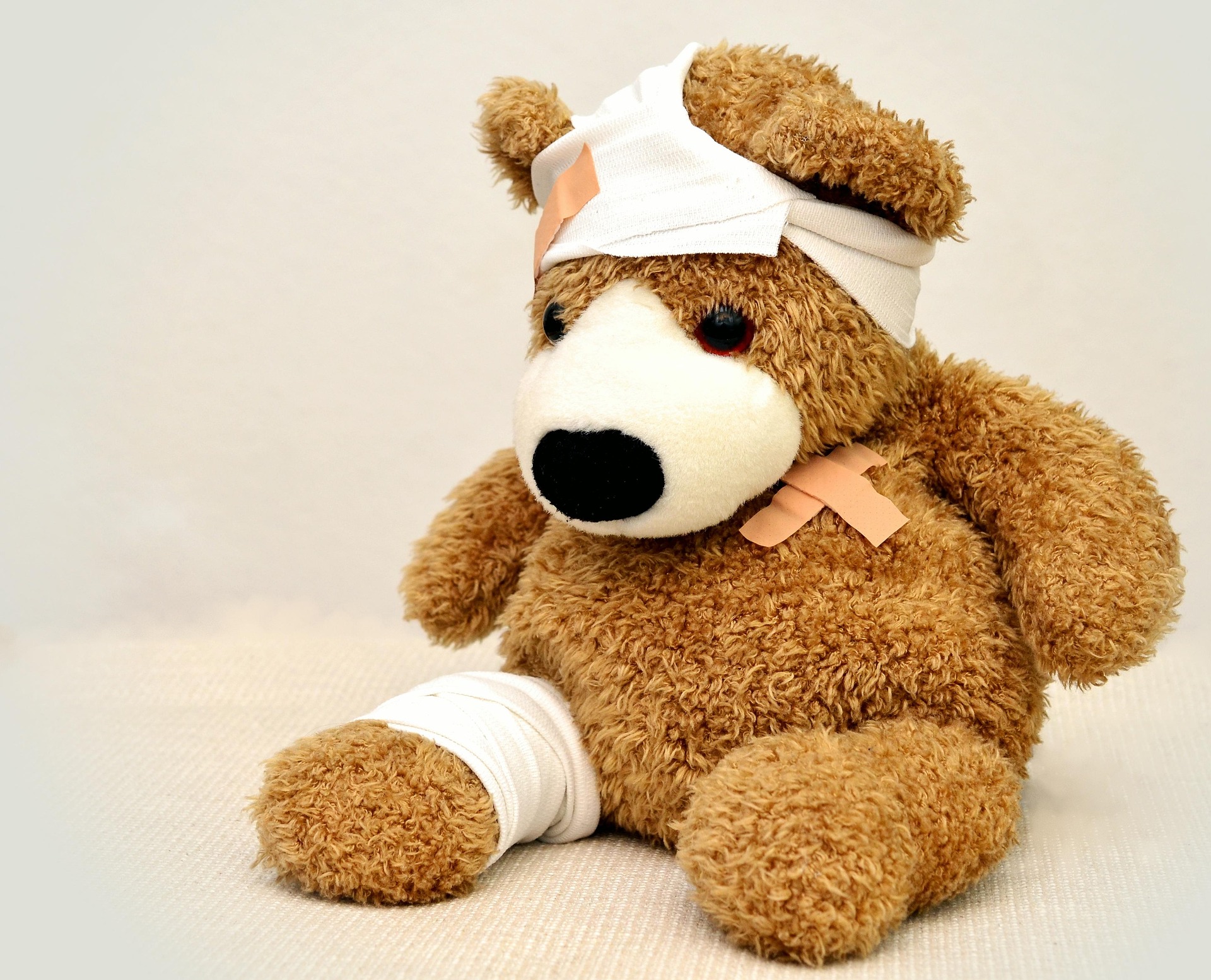 Stuffed brown teddy bear with bandages.