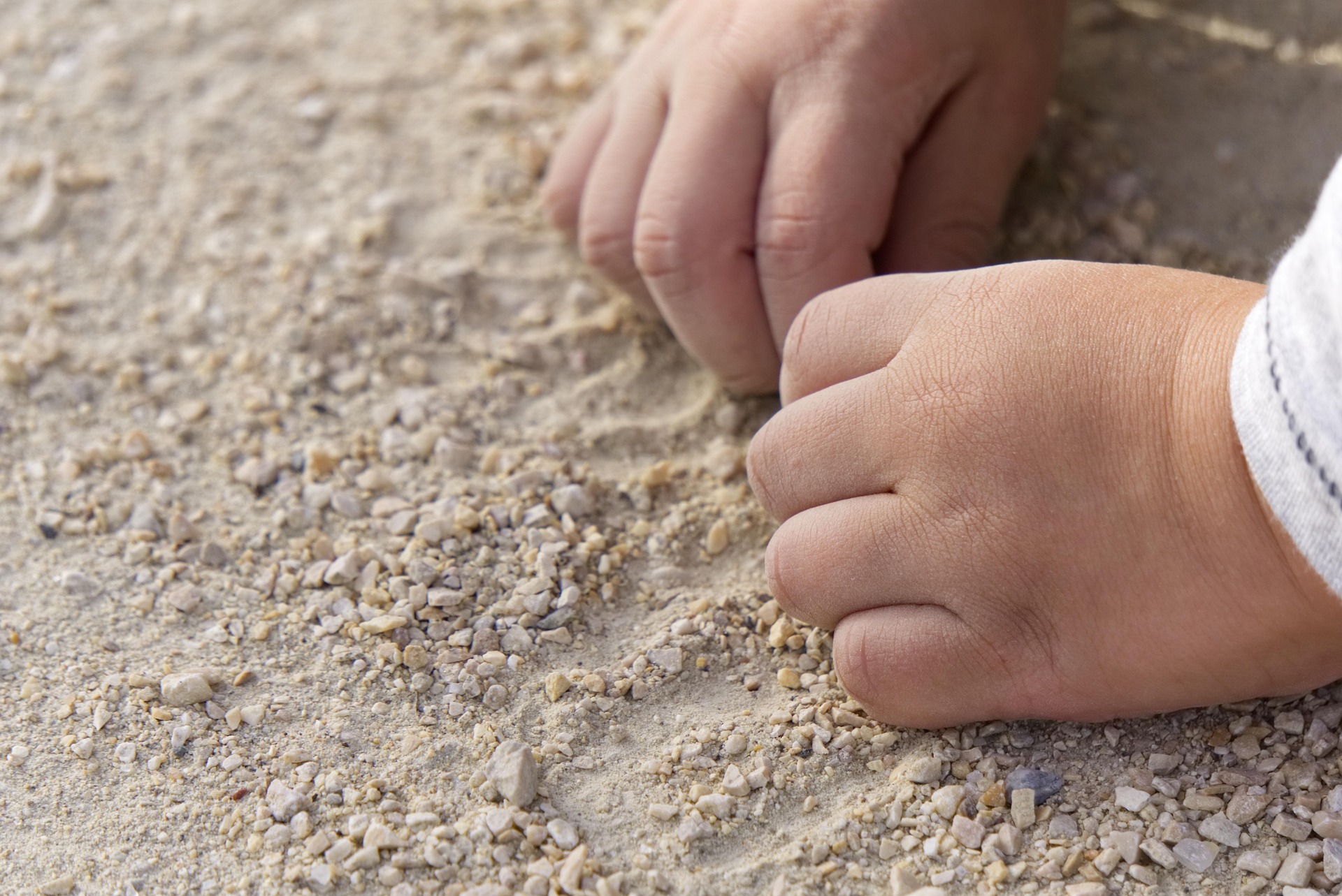 toddler hands in a sand box