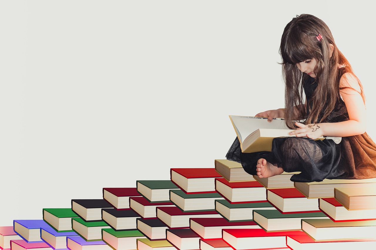 Girl reading a book at the top of a stack of books