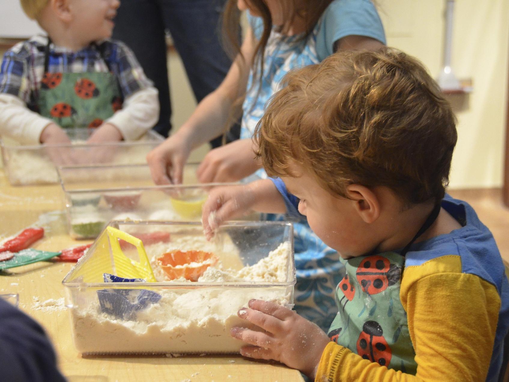 Child playing with a sand sensory bin.