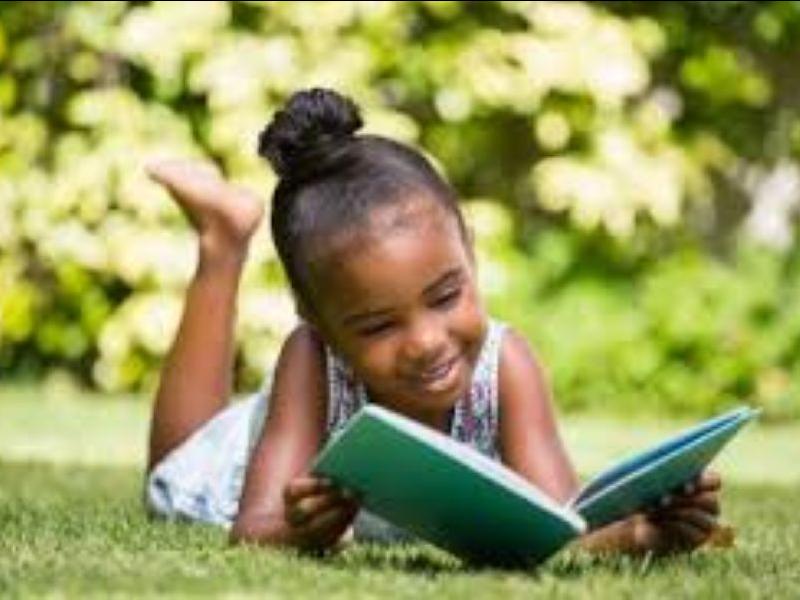 Little girl reading outside