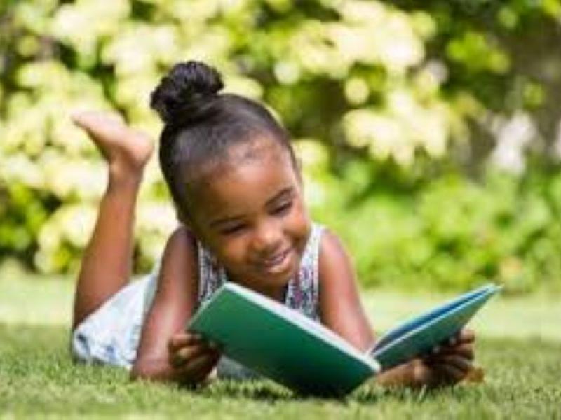 Little girl reading outside.