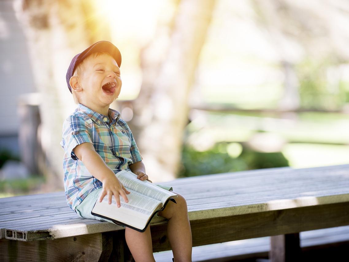Photo of a young boy reading and laughing.