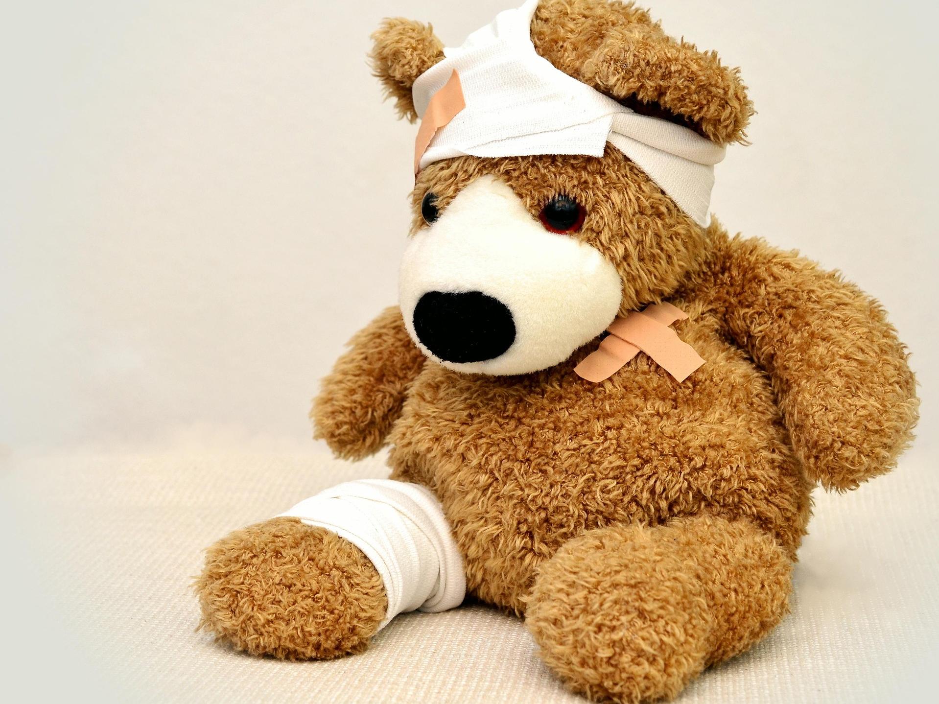 Stuffed brown teddy bear with bandages.