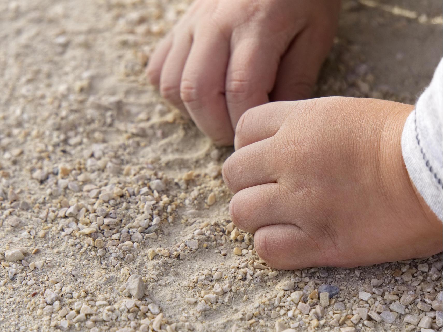 toddler hands in a sand box